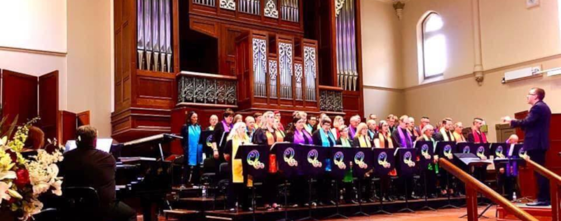 A legacy photo of the choir, performing in front of a large pipe organ